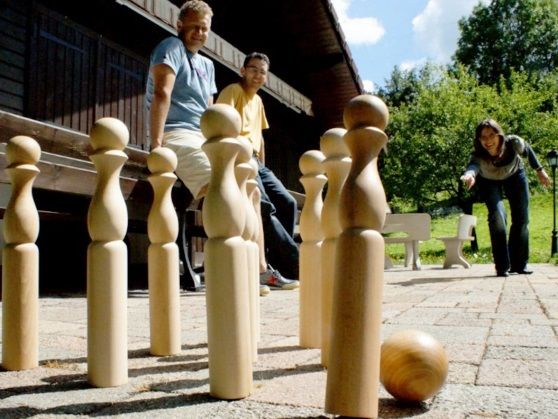 Groupe de personnes jouant au bowling en bois sur une terrasse