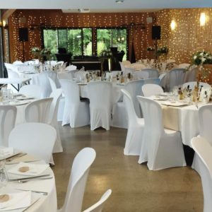 Salle de mariage avec tables et chaises blanches et rideaux leds sur le mur