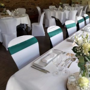 Repas de mariage avec chaises housses blanches et déco végétale verte